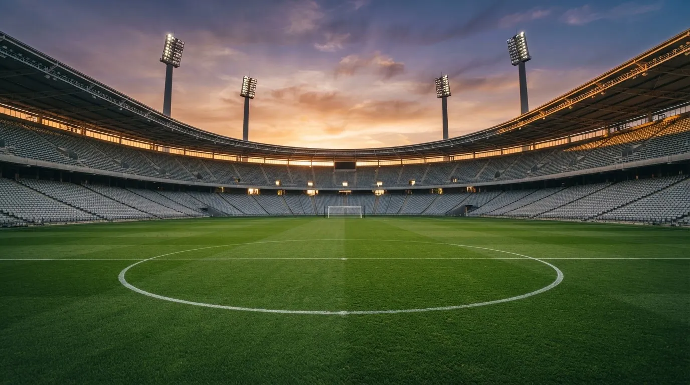 Un estadio de fútbol vacío con torres de iluminación al atardecer