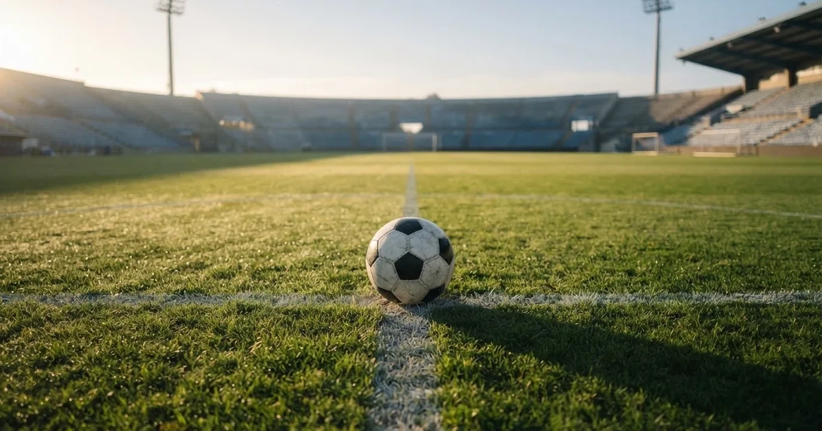 Un balón en el punto central de un campo de césped a la luz de la mañana