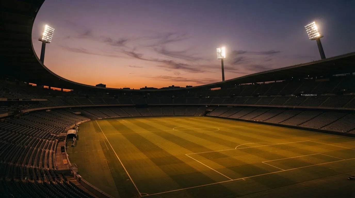 Un estadio de fútbol vacío con torres de iluminación al atardecer