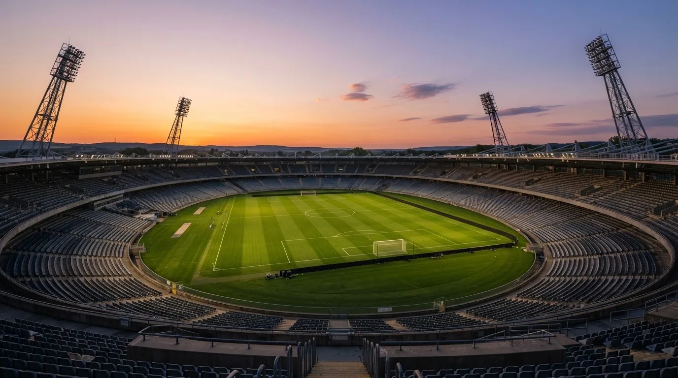 Un estadio de fútbol vacío con torres de iluminación al atardecer