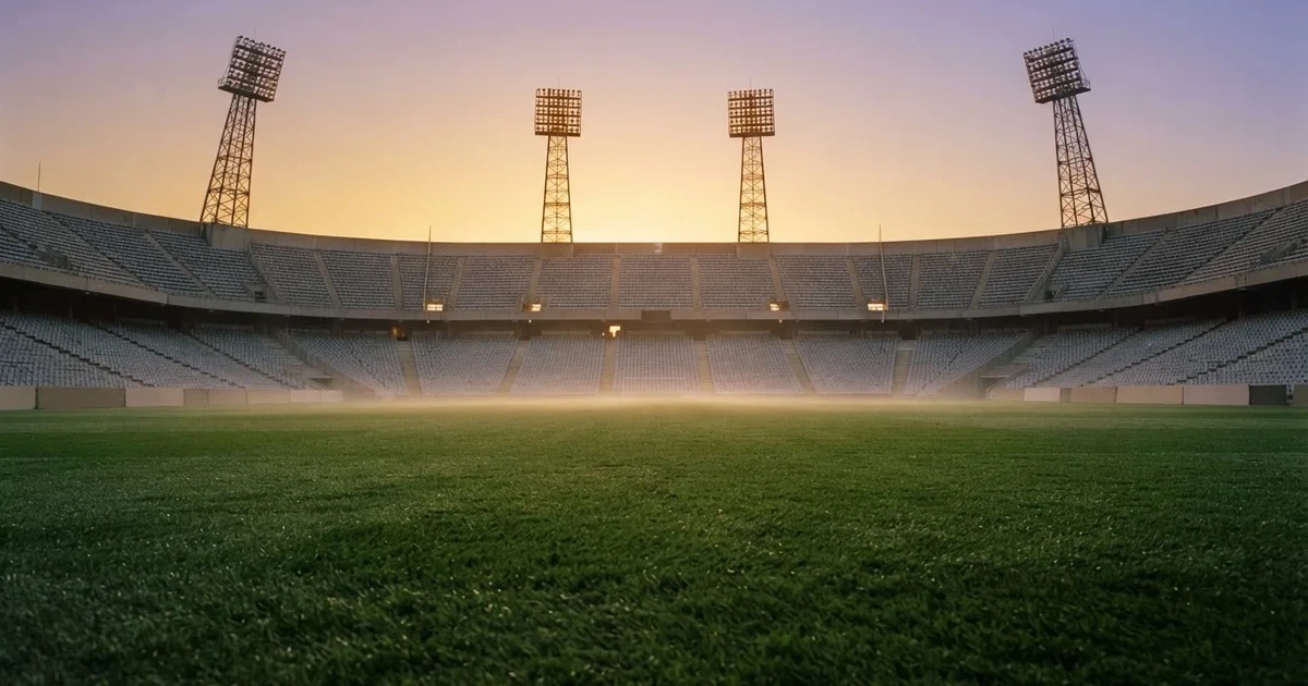 Un estadio de fútbol vacío con torres de iluminación al atardecer