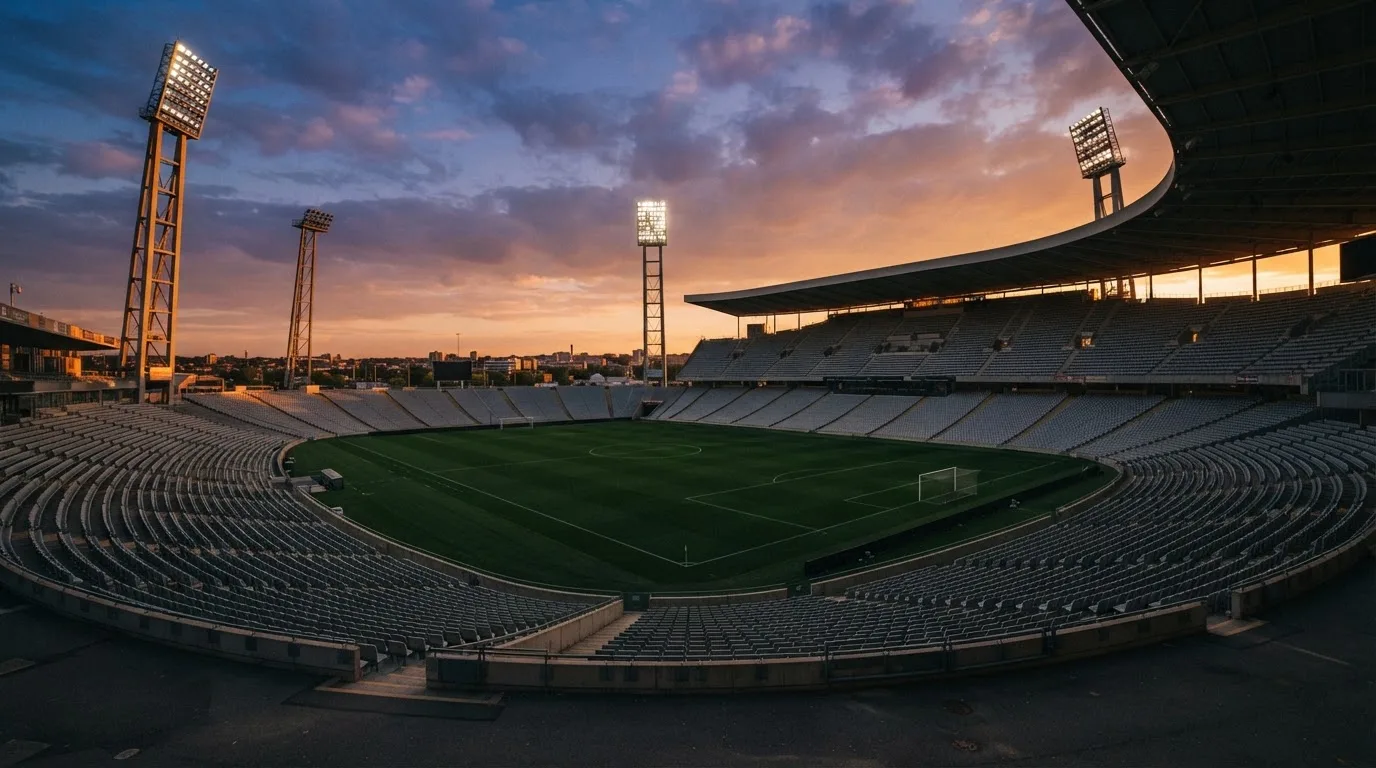 Un estadio de fútbol vacío con torres de iluminación al atardecer