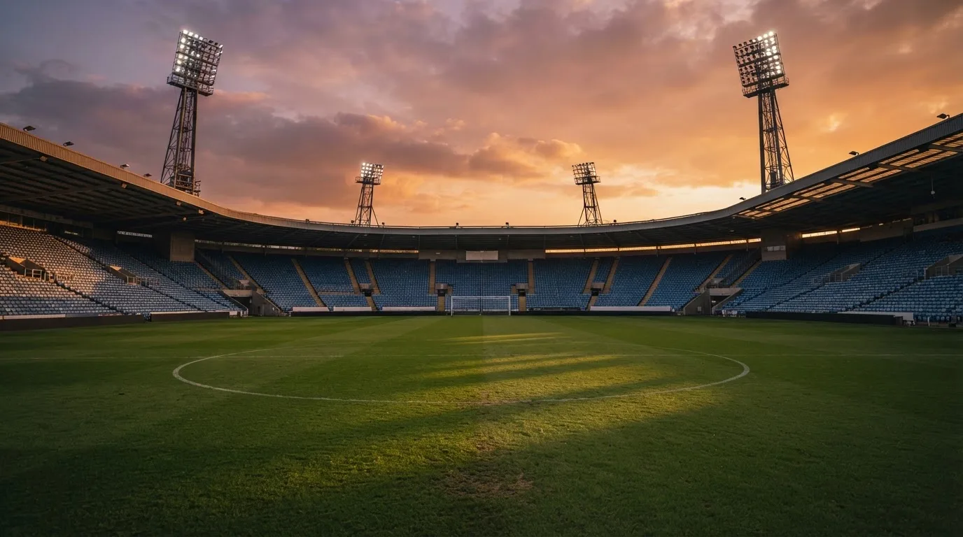 Un estadio de fútbol vacío con torres de iluminación al atardecer