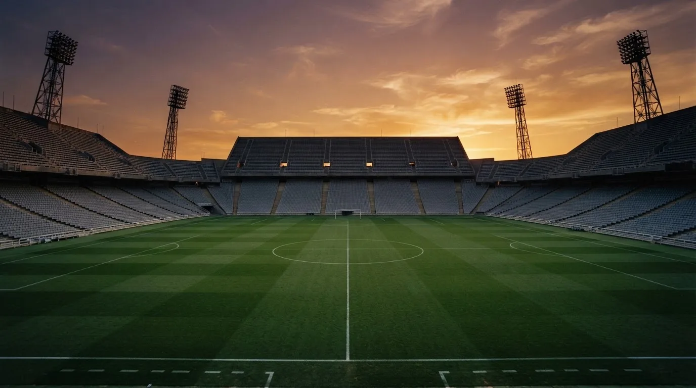 Un estadio de fútbol vacío con torres de iluminación al atardecer