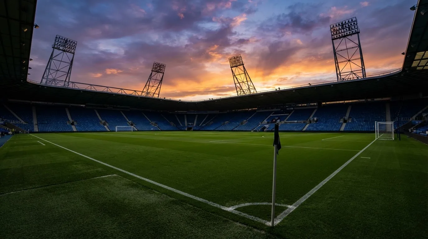 Un estadio de fútbol vacío con torres de iluminación al atardecer