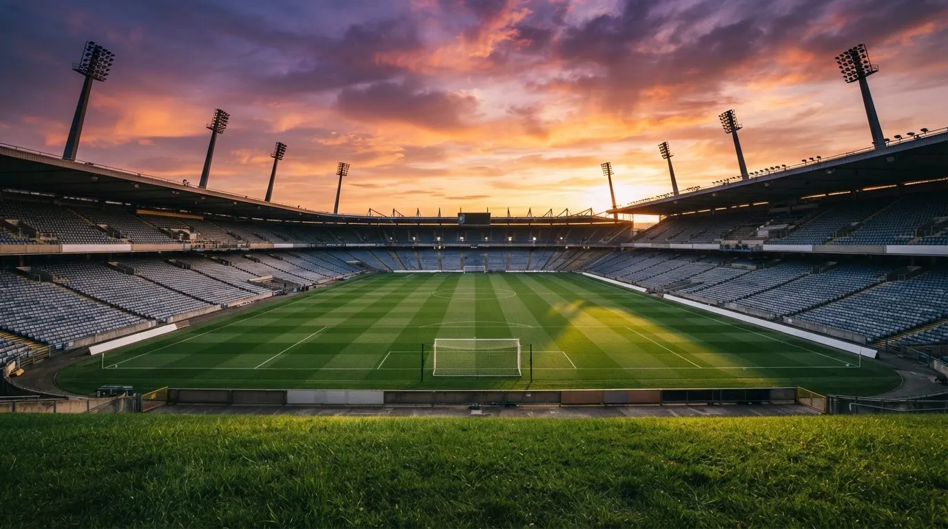 Un estadio de fútbol vacío con torres de iluminación al atardecer