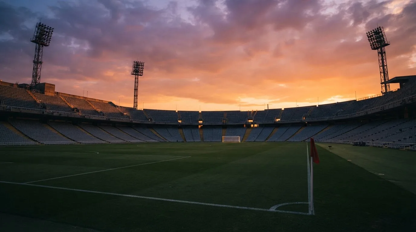 Un estadio de fútbol vacío con torres de iluminación al atardecer