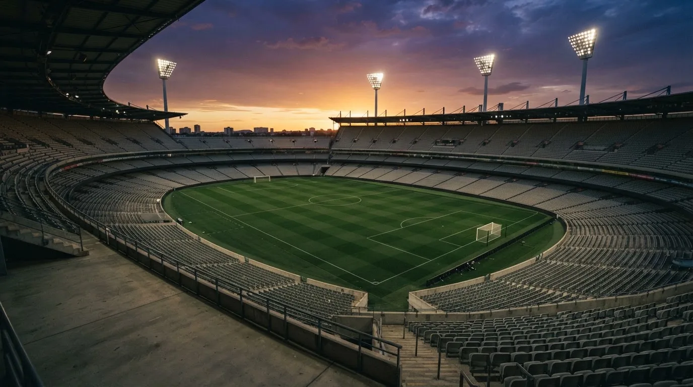 Un estadio de fútbol vacío con torres de iluminación al atardecer