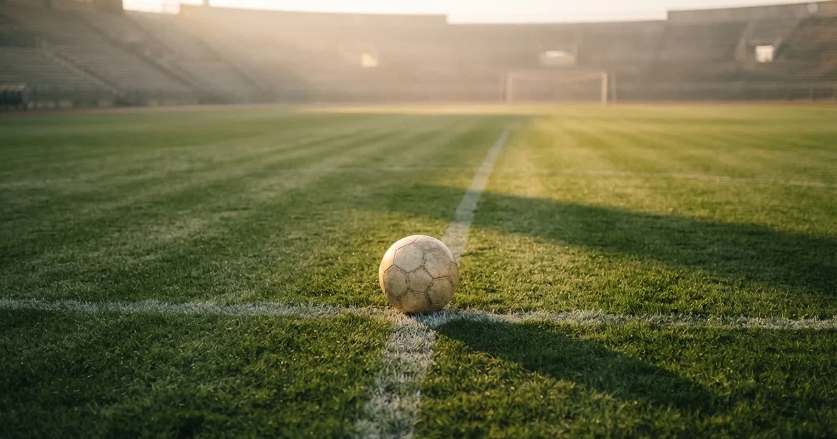 Un balón en el punto central de un campo de césped a la luz de la mañana