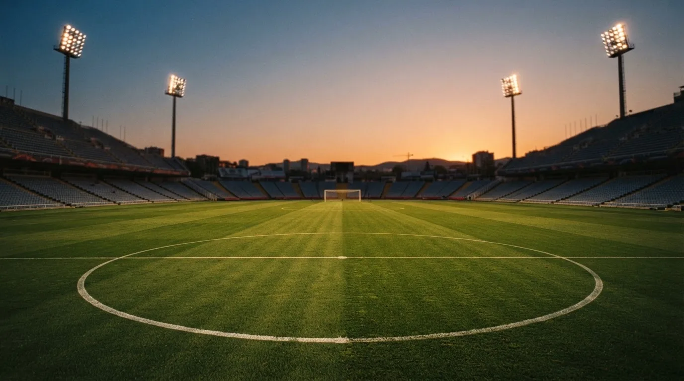 Un estadio de fútbol vacío con torres de iluminación al atardecer