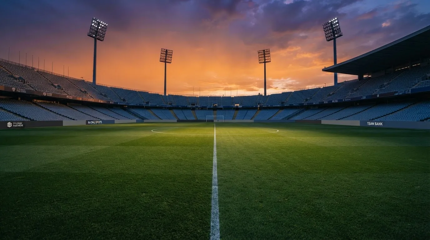 Un estadio de fútbol vacío con torres de iluminación al atardecer