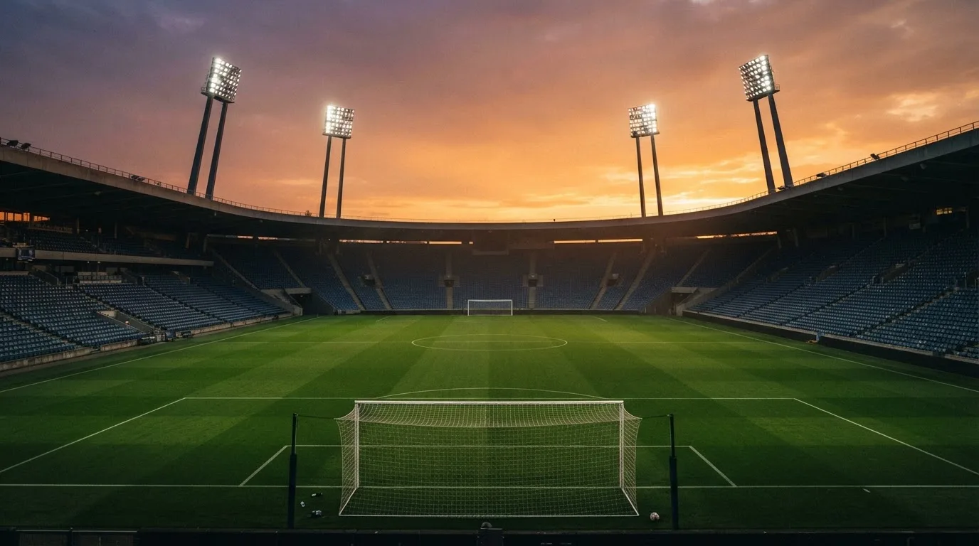 Un estadio de fútbol vacío con torres de iluminación al atardecer