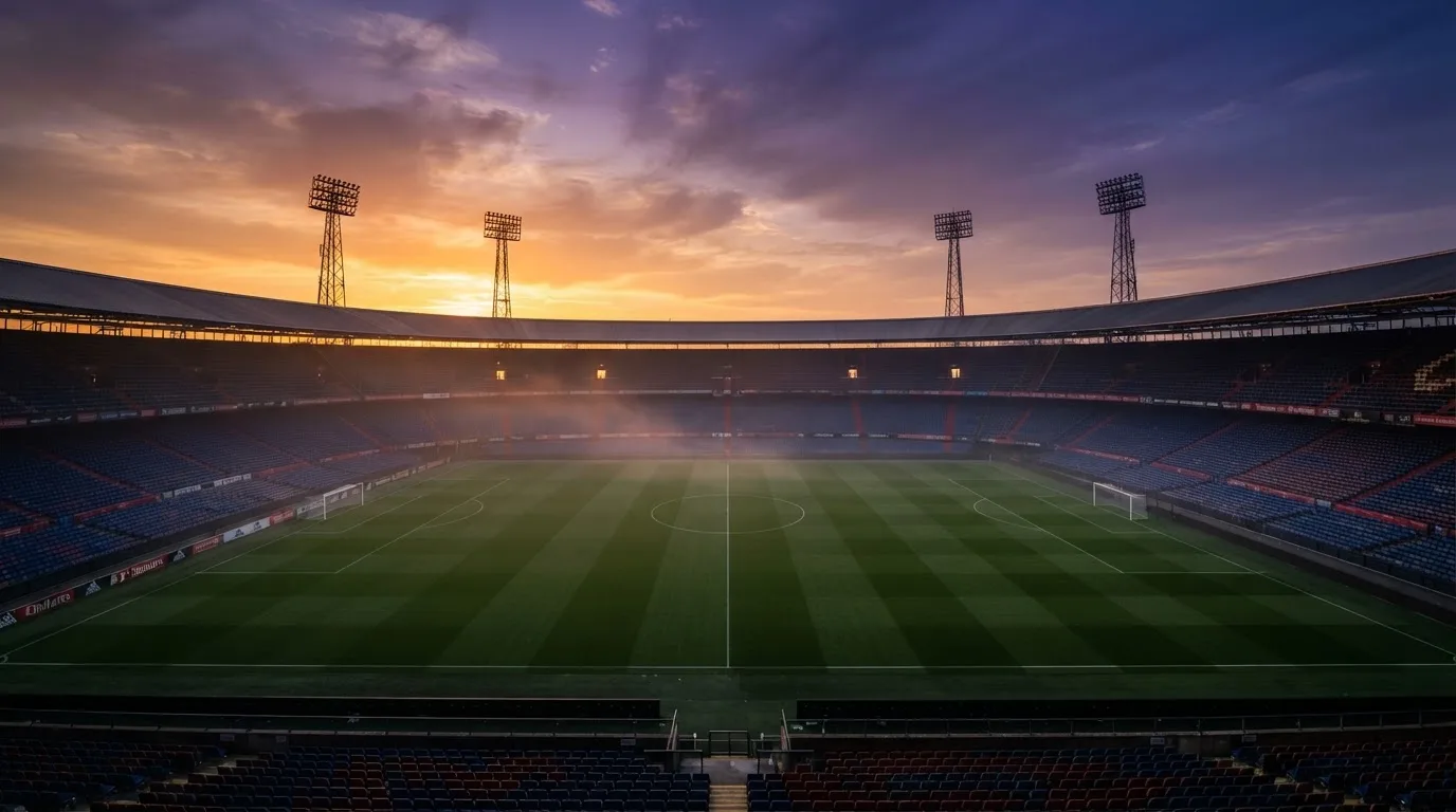 Un estadio de fútbol vacío con torres de iluminación al atardecer