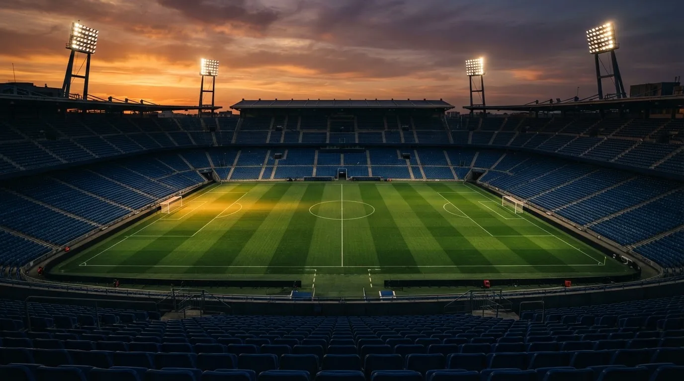 Un estadio de fútbol vacío con torres de iluminación al atardecer