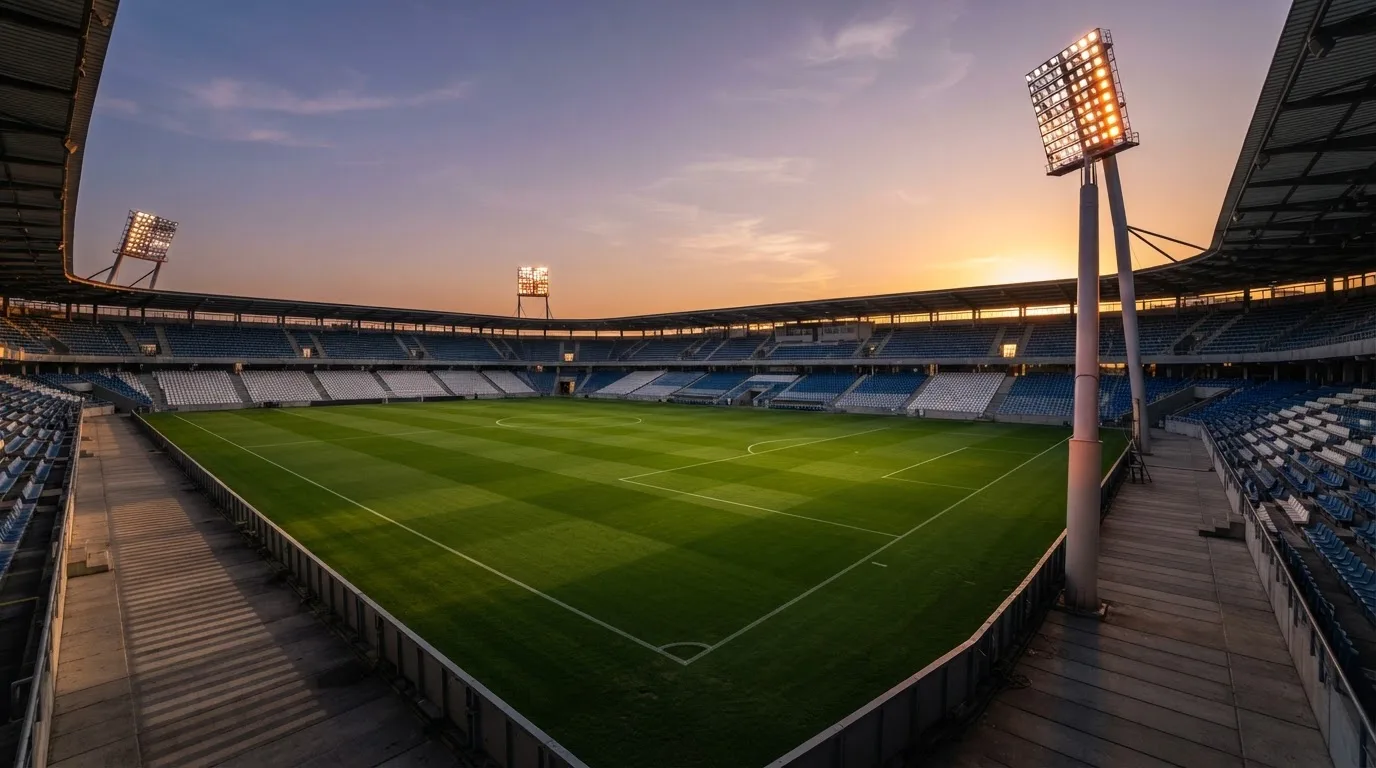 Un estadio de fútbol vacío con torres de iluminación al atardecer