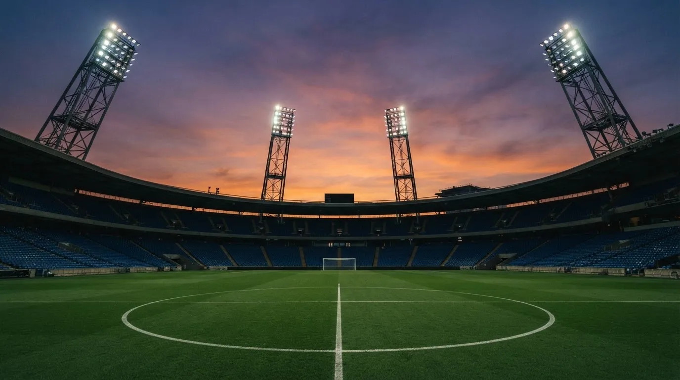 Un estadio de fútbol vacío con torres de iluminación al atardecer
