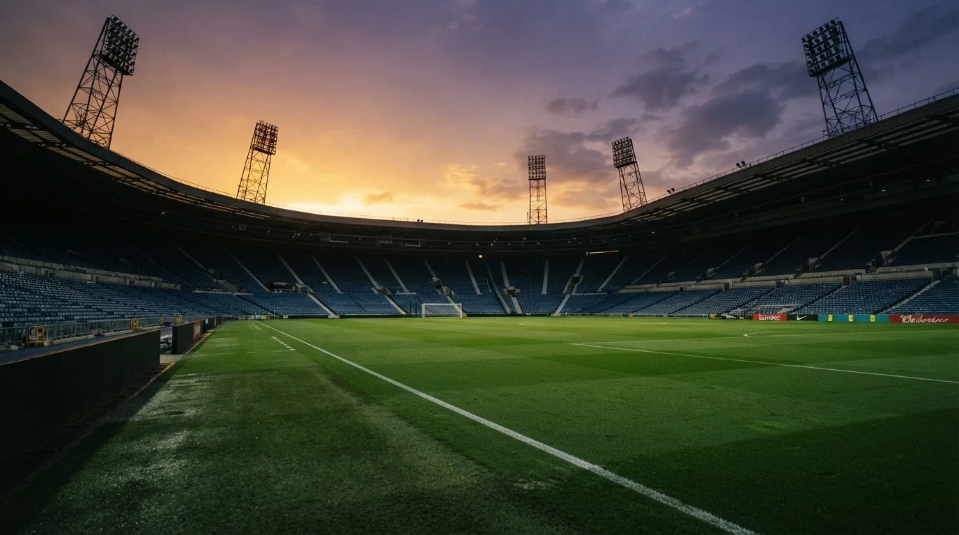 Un estadio de fútbol vacío con torres de iluminación al atardecer