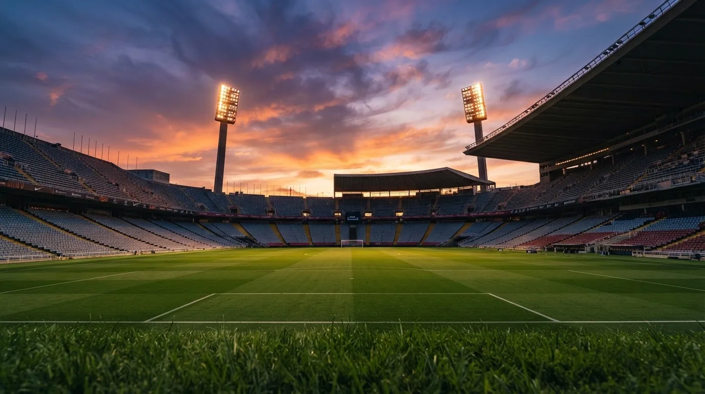 Un estadio de fútbol vacío con torres de iluminación al atardecer